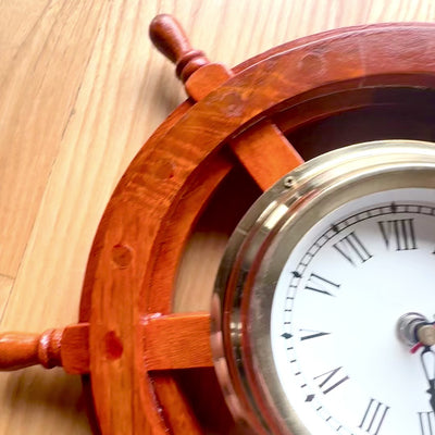 Maritieme klok in een houten stuurwiel van messing